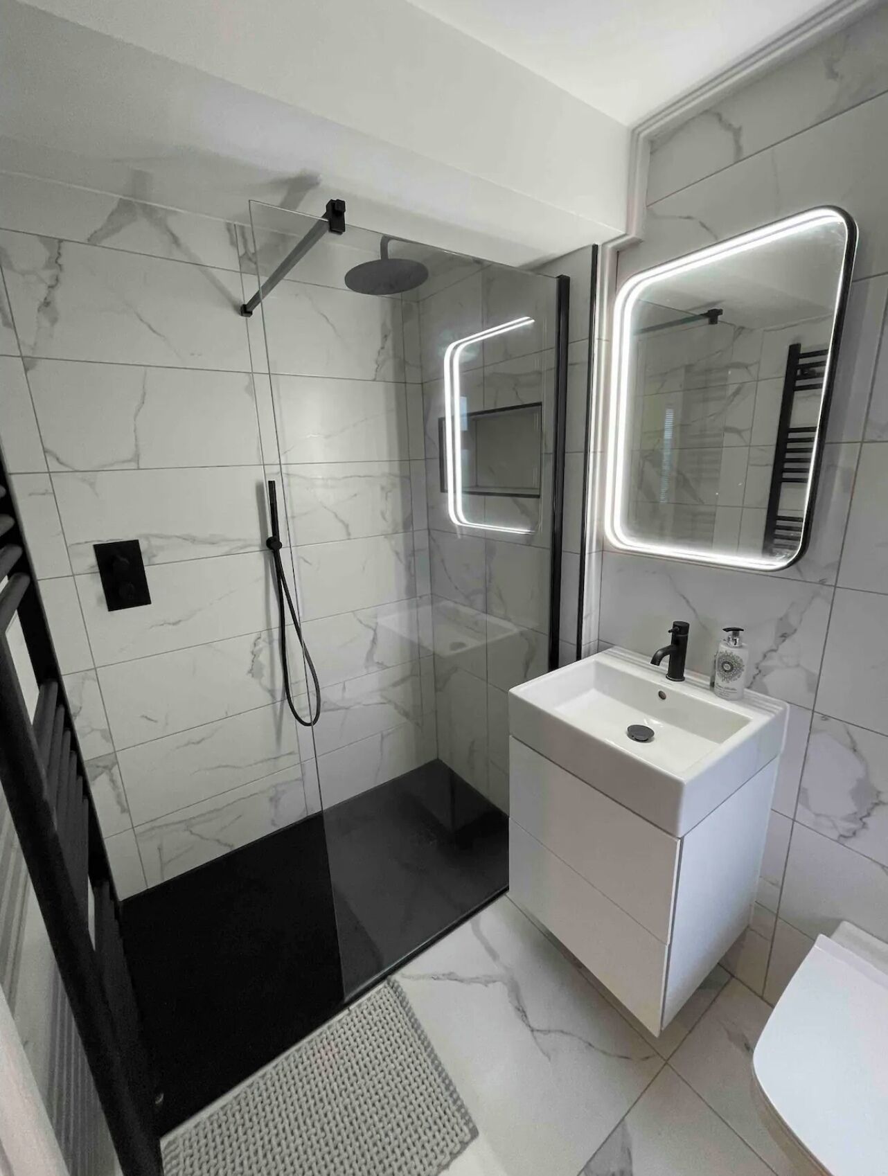 A modern bathroom with a walk-in shower, a vanity with a mirror, and a toilet.