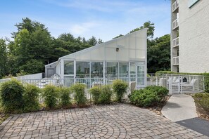 Ein modernes Gebäude mit Glasfassade, umgeben von einem weißen Zaun und viel Grün.