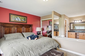 A bedroom with a large bed, a nightstand, a dresser, a mirror, and a painting on the wall. - 2 BR | Indoor Pool | Hot Tub Access | Mtn View (Pigeon Forge)