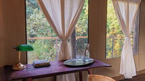 A wooden table with a tray, a green desk lamp, a book titled "Zambia," and a glass set. - Camp Sabali & Safaris (South Luangwa National Park)