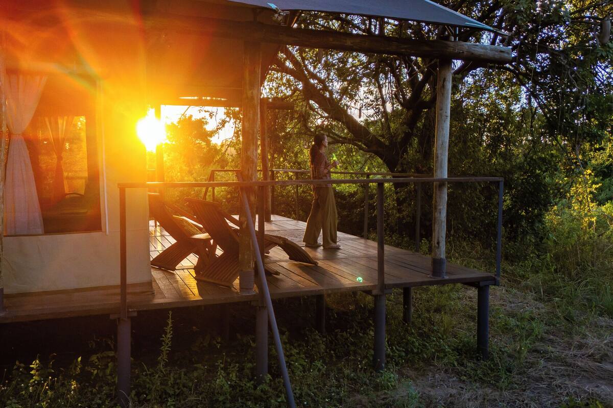 Eine Holzterrasse mit Sonnenuntergangsblick, einem überdachten Sitzbereich und einer rustikalen Gebäudestruktur.