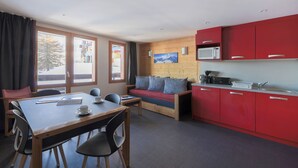 Un espace de vie compact comprenant un coin repas, un canapé et une kitchenette.