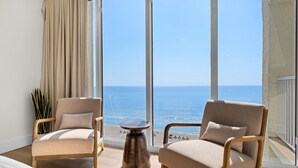 A balcony with two armchairs, a small table, and a view of the sea. - LAGOON POOL OPEN!! TOTAL REMODEL! THREE BEDROOM AT LONG BEACH (Panama City Beach)