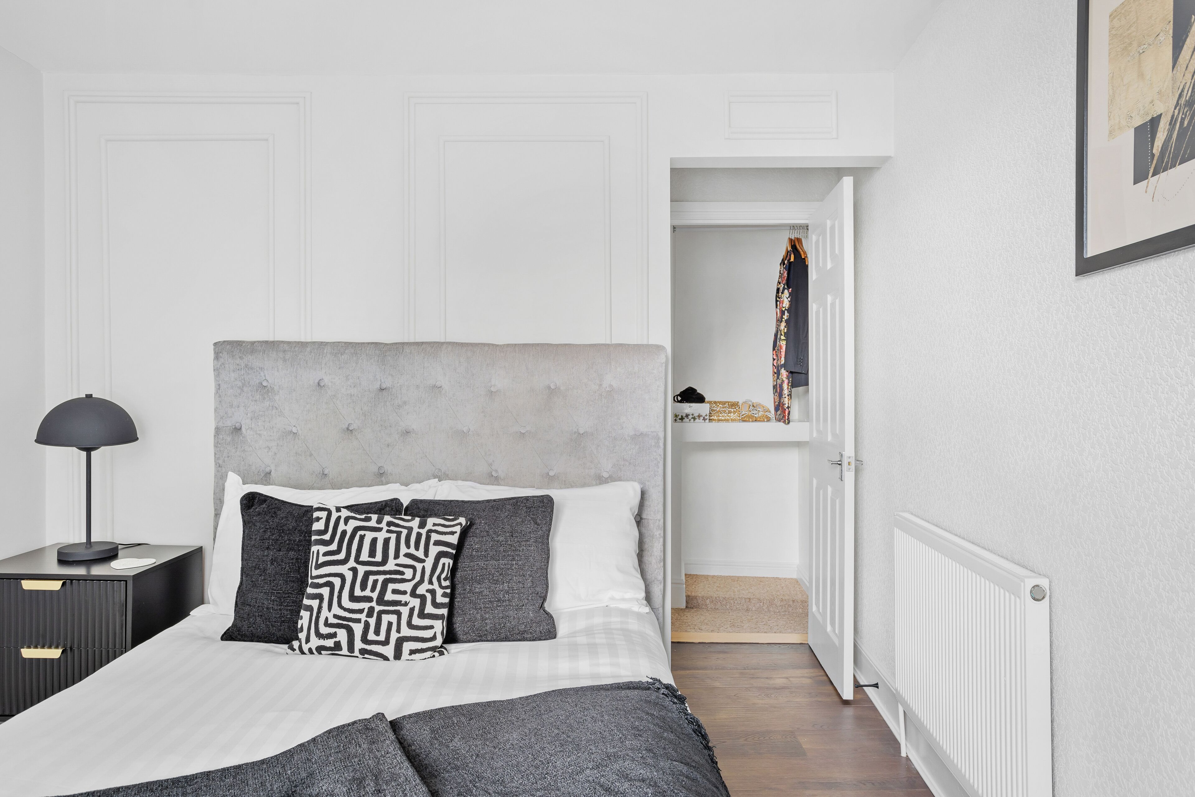 A bedroom with a bed, a nightstand, a lamp, and a door leading to a closet.