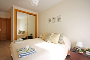 Ein Hotelzimmer mit einem großen Bett, einem Holzschrank, einem Nachttisch mit Lampe und drei gerahmten Bildern an der Wand.