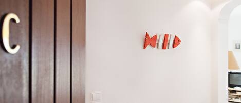 Une pièce avec une porte en bois, un mur blanc et un élément décoratif en forme de poisson.