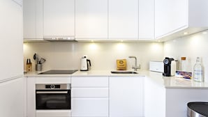 A modern kitchen with white cabinets, a built-in oven, a coffee maker, and a kettle. - Townhouse in Tavira With 2 Bedrooms and 2 Bathrooms (Tavira)