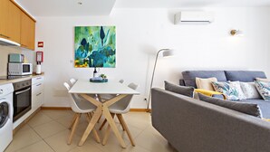 Una cocina moderna con una mesa y sillas, un sofá gris y un cuadro abstracto y colorido en la pared.