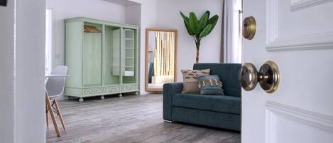 A room with a green wardrobe, a blue sofa, and a large plant.