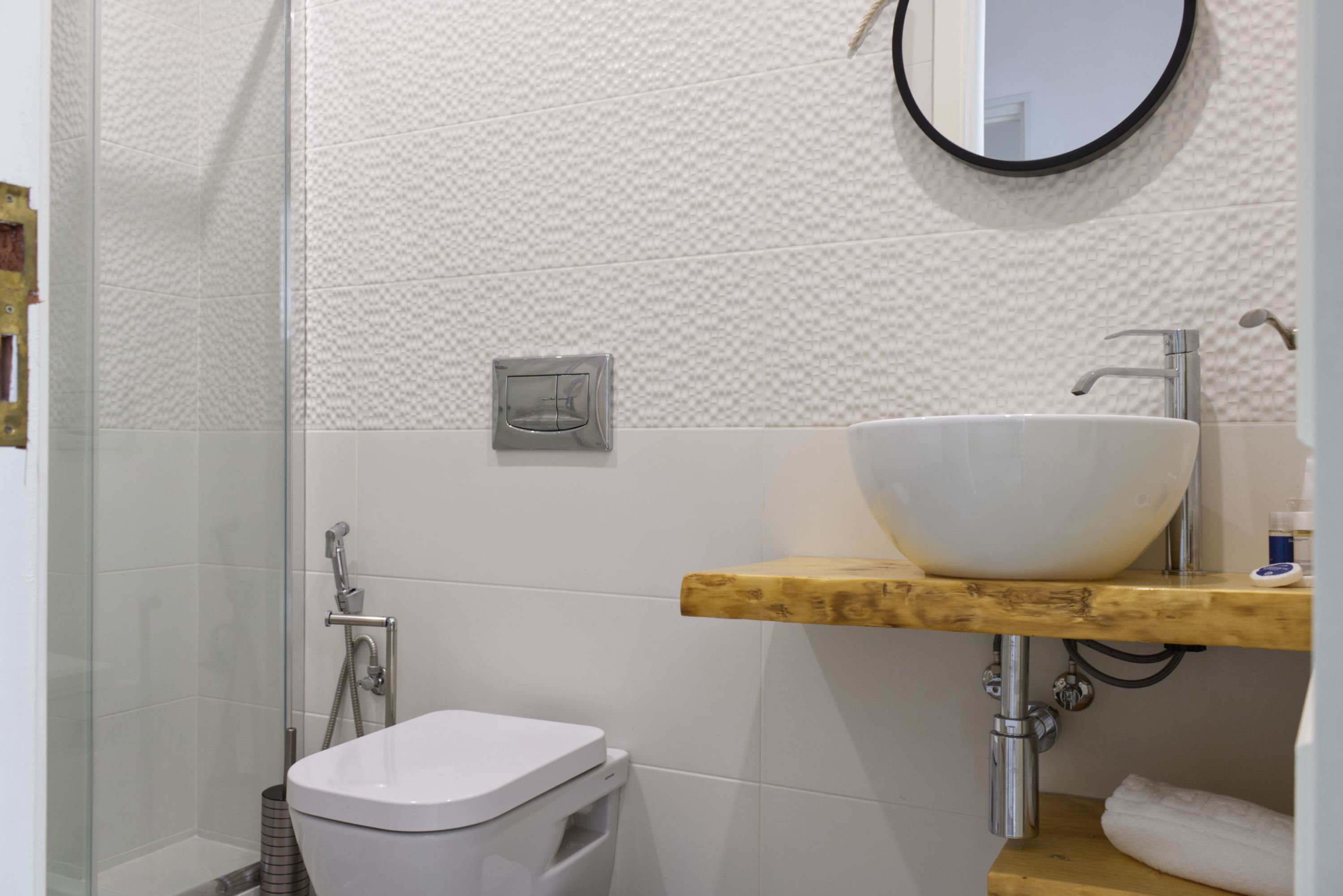 Un bagno con un water bianco, un mobile bagno in legno, un lavandino bianco e uno specchio.