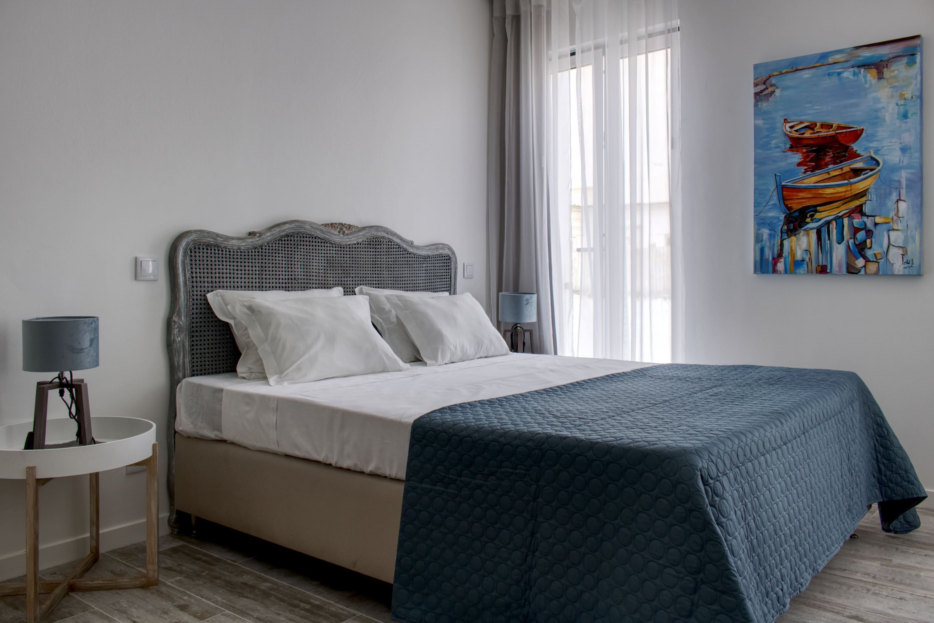 A bedroom with a bed, a bedside table, a lamp, and a painting on the wall.