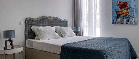 A bedroom with a bed, a bedside table, a lamp, and a painting on the wall.