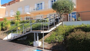 Un edificio de varios pisos con una terraza de madera y una piscina pequeña.