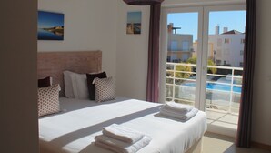 Habitación de hotel con una cama grande, vista a una piscina y un balcón.