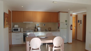 Een moderne keuken met houten kastjes, een eettafel met stoelen en een magnetron.