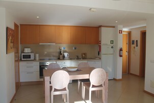 Cozinha moderna com armários de madeira, uma mesa de jantar com cadeiras e um micro-ondas.