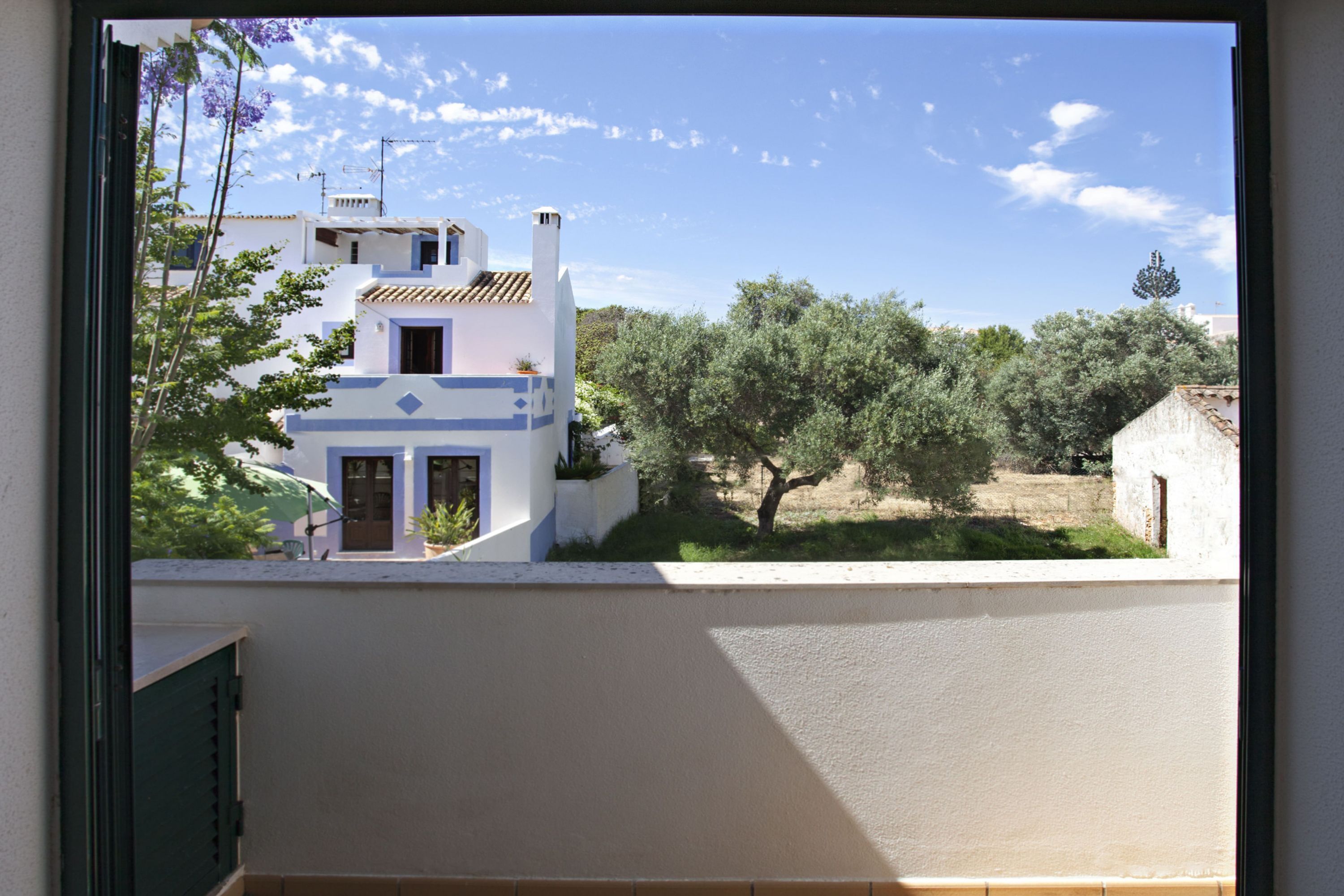 A view from a window overlooking a building with a tiled roof and a balcony.