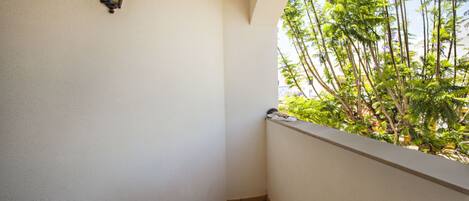 A corner of a balcony with a tiled floor and a wall-mounted light fixture.