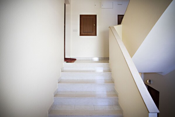 Un escalier avec un mur de couleur beige et une porte en bois en haut.