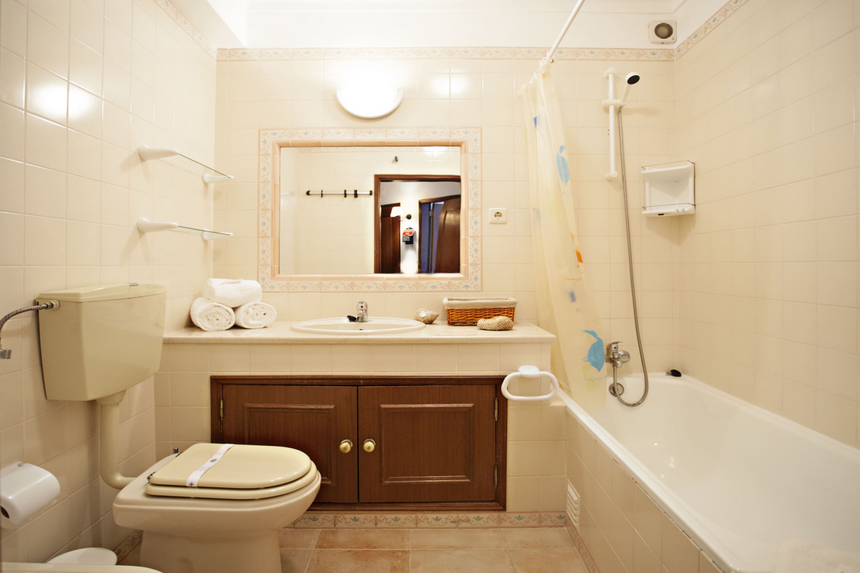 A bathroom with a toilet, sink, mirror, and bathtub.