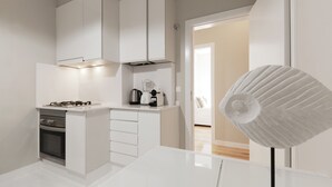 A modern kitchen with white cabinetry, a gas stove, a coffee maker, and a unique white fan. - Andrade in Lisboa Ciudad (Lisbon)