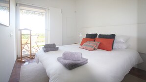 Une chambre avec un grand lit, une porte donnant sur un balcon et un porte-serviettes.
