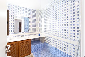 A bathroom with blue and white patterned tiles, a wooden vanity, and a mirror. - Casa Z lia in Tavira (Tavira)