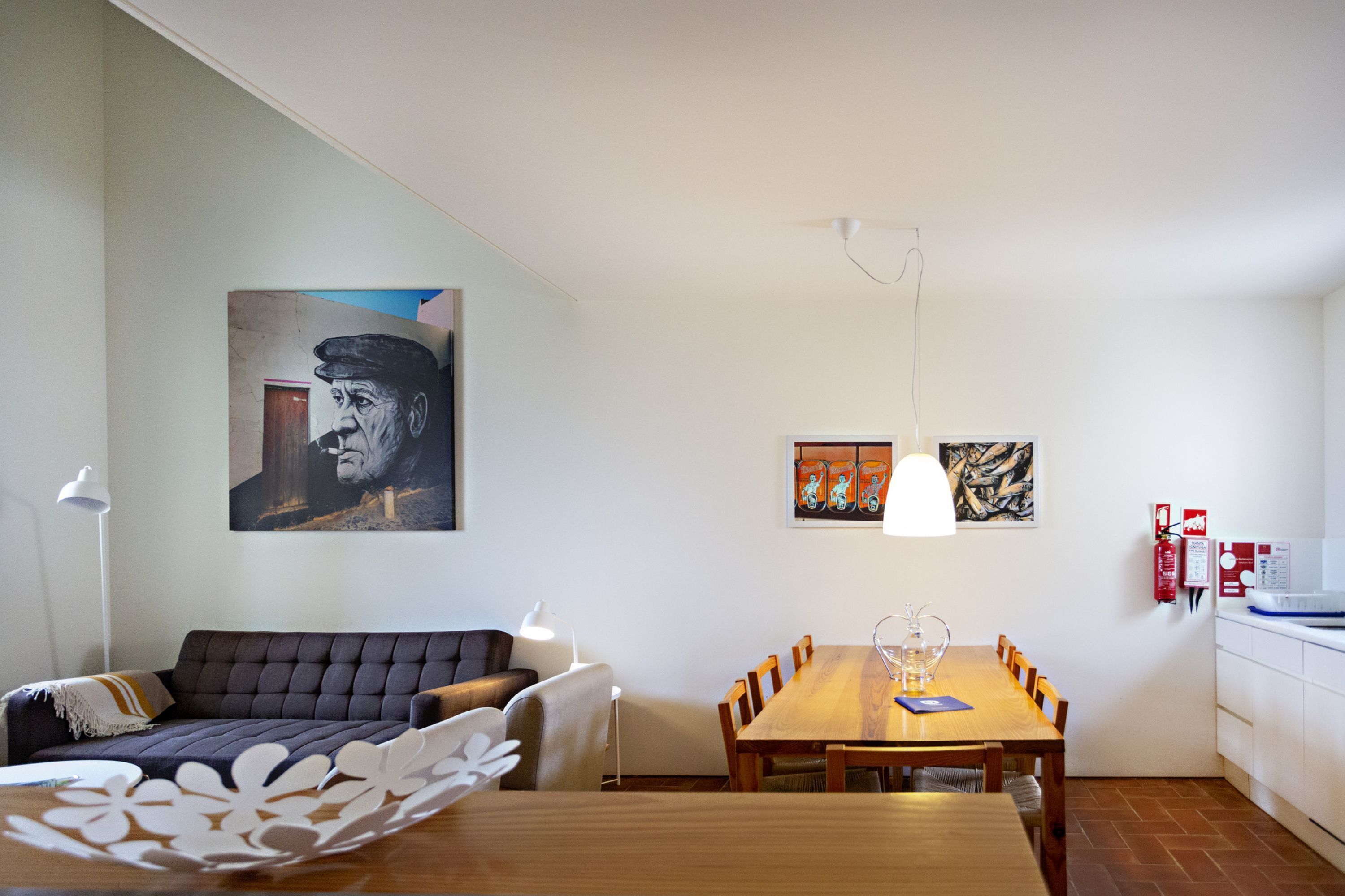 A dining area with a wooden table and chairs, a sofa, and a painting on the wall.