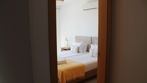 A bedroom with a bed, a nightstand, and a lamp. - CG 71M - Dplx Garden - Cabanas Gardens (Tavira)