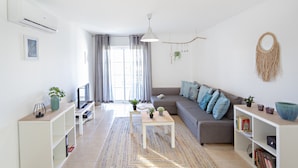 Ett modernt vardagsrum med en soffa, ett soffbord, en tv och en bokhylla.