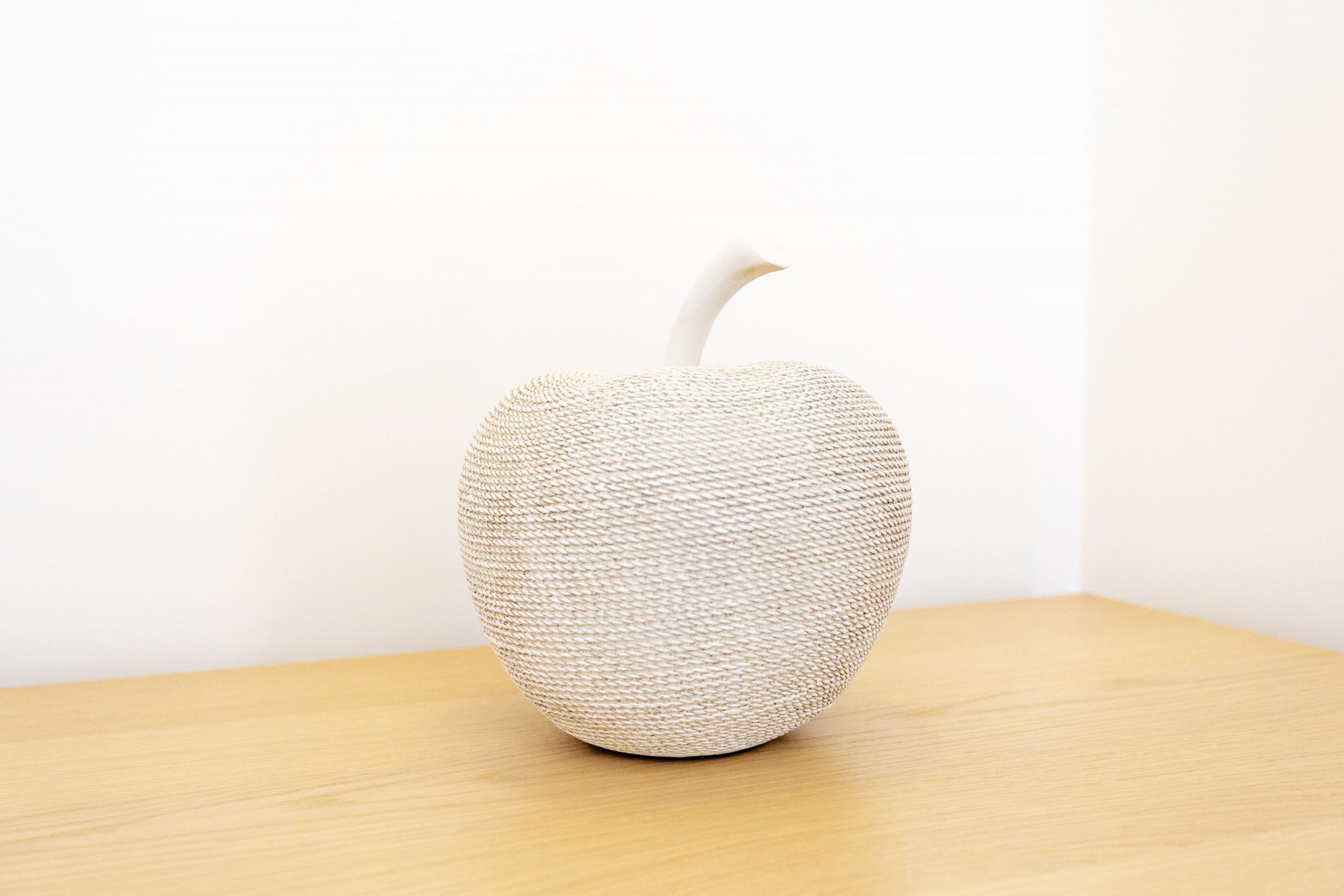 A textured, spherical object with a curved top, placed on a wooden surface against a plain background.