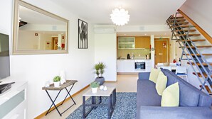 Un salon moderne avec un canapé, une table à manger et une cuisine en arrière-plan.