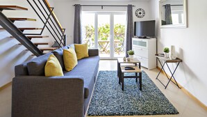 Un salon moderne avec un canapé, une table basse, un téléviseur et un escalier.