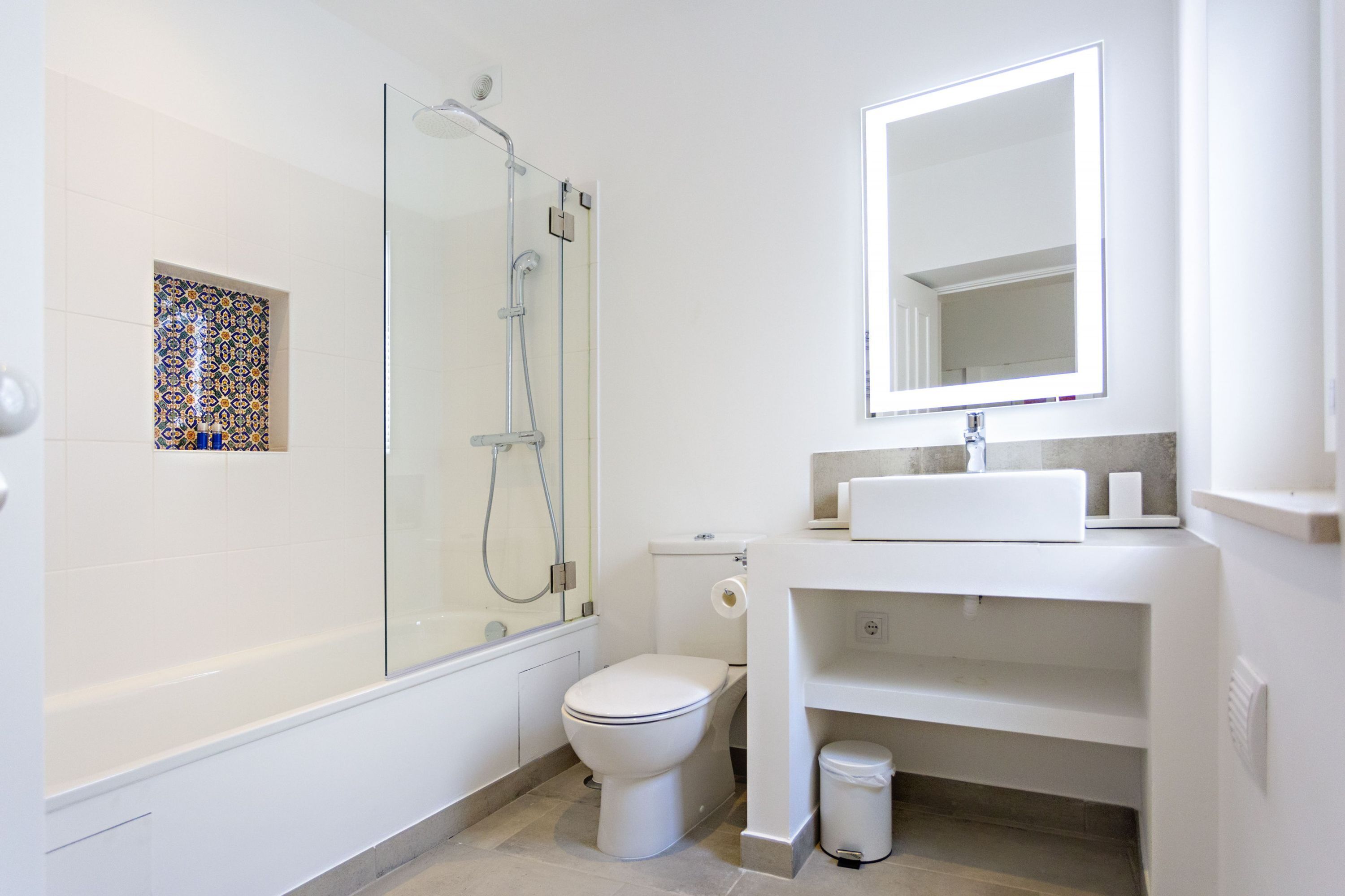 A modern bathroom with a glass shower enclosure, a toilet, and a sink with a mirror above it.