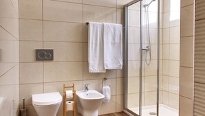 A modern bathroom with a toilet, bidet, and glass-enclosed shower. - S qua - Apt do Rio (Tavira)