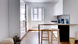A modern kitchen with wooden flooring, a window, and a built-in stove. - S qua - Apt do Rio (Tavira)