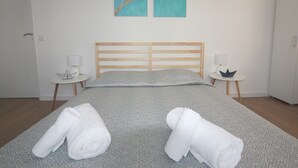 A neatly made bed with a patterned bedspread, two white towels, and a wooden headboard. There are two bedside tables with lamps and decorative items.