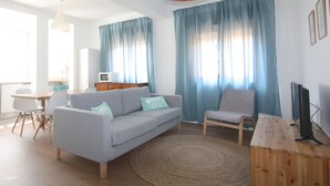 A living room with a sofa, a chair, a TV, and a wooden desk. - Jara in Tavira With 3 Bedrooms and 1 Bathrooms (Tavira)