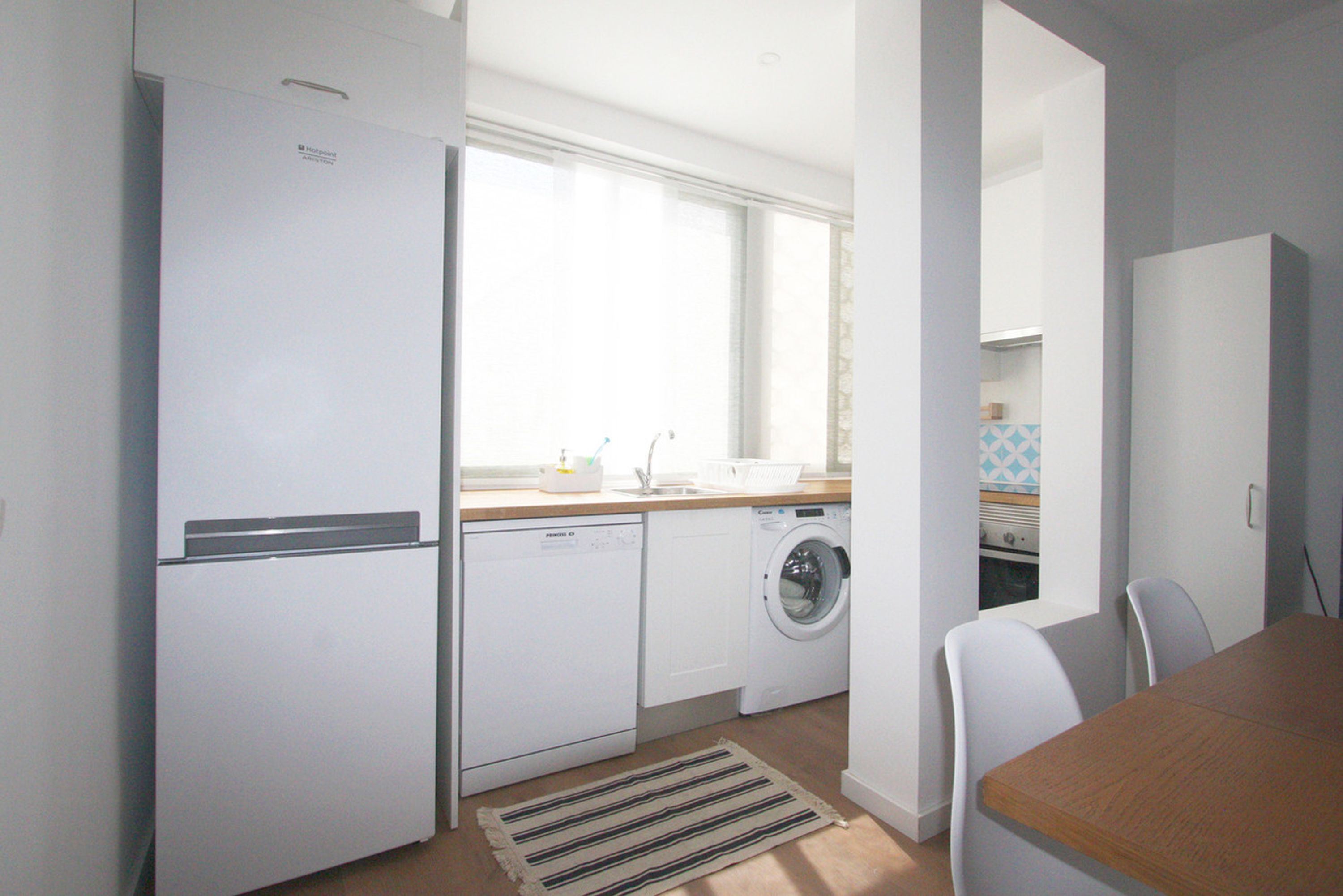 A compact kitchen with a refrigerator, dishwasher, and washing machine.