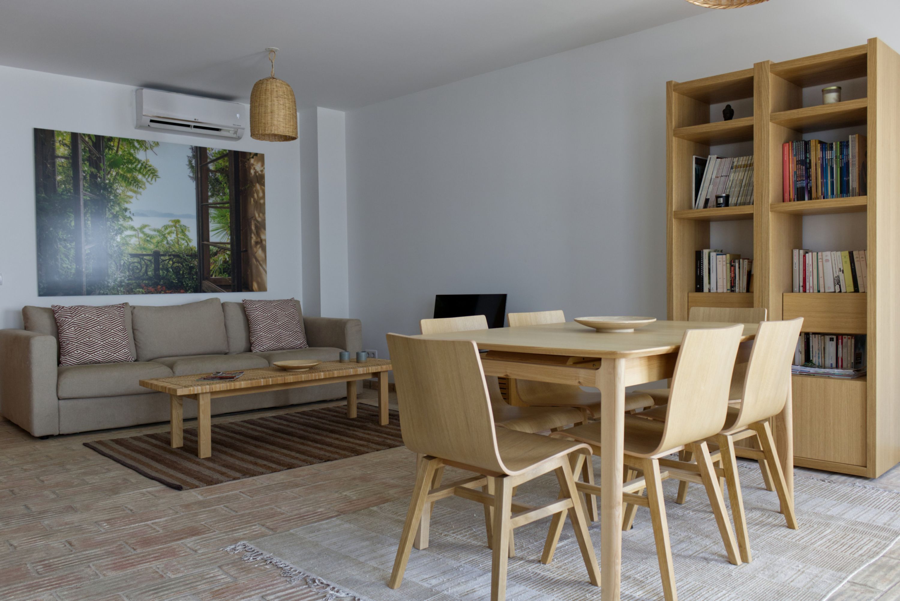 A modern living room with a sofa, coffee table, dining table, chairs, and a bookshelf.