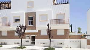 Un moderno edificio de dos pisos con techo plano, múltiples ventanas y un pequeño balcón.