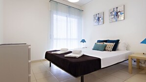 Une chambre d’hôtel avec un lit, un bureau, une chaise, une fenêtre avec des rideaux et des œuvres d’art accrochées au mur.