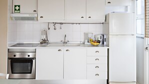 Une cuisine moderne avec des meubles blancs, un four en acier inoxydable, un évier et un réfrigérateur.