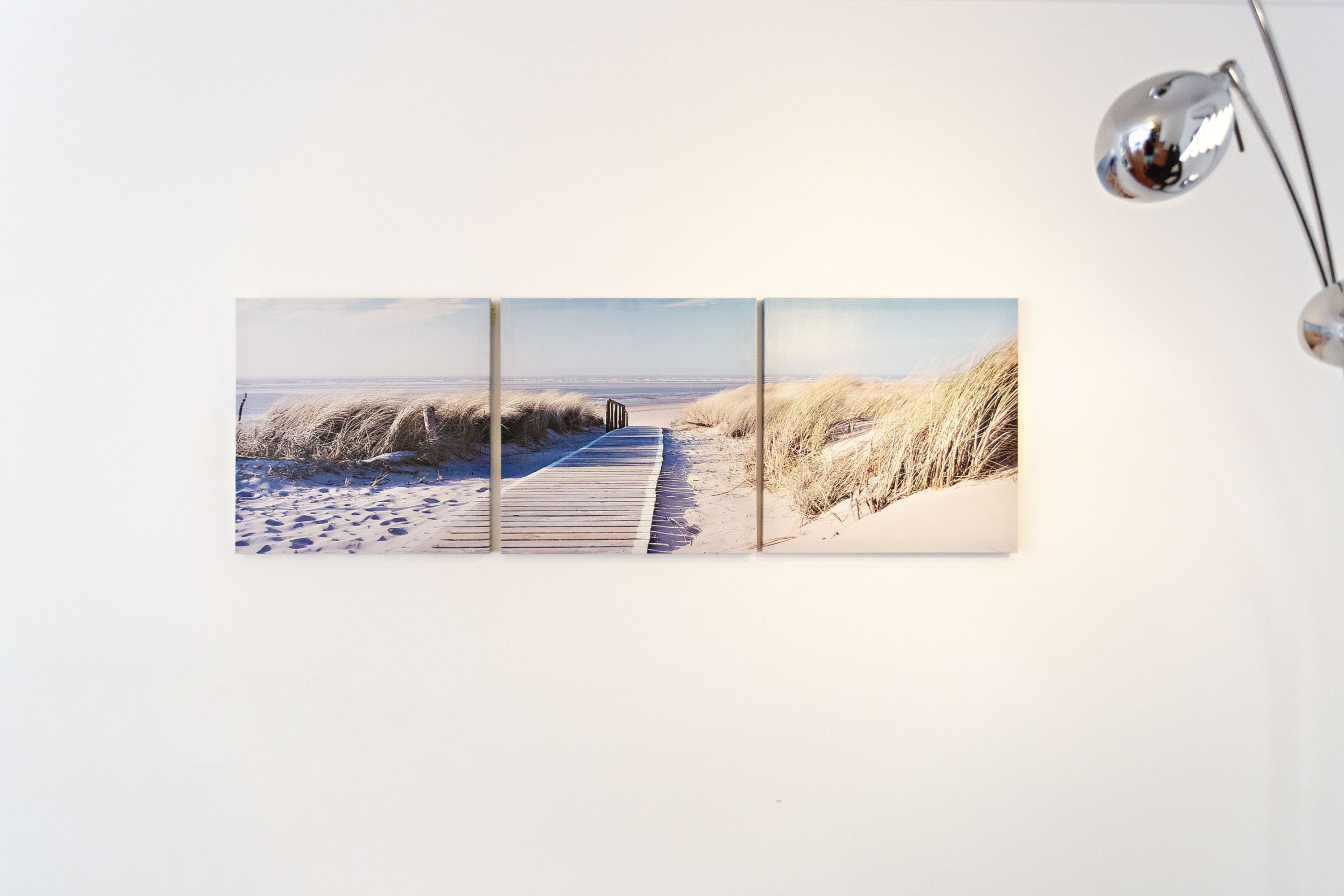 A three-panel artwork of a beach pathway with dunes.