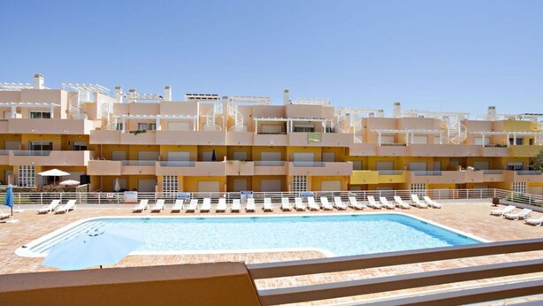 Ein Hotel mit Schwimmbad, mehreren Balkonen und Liegestühlen.
