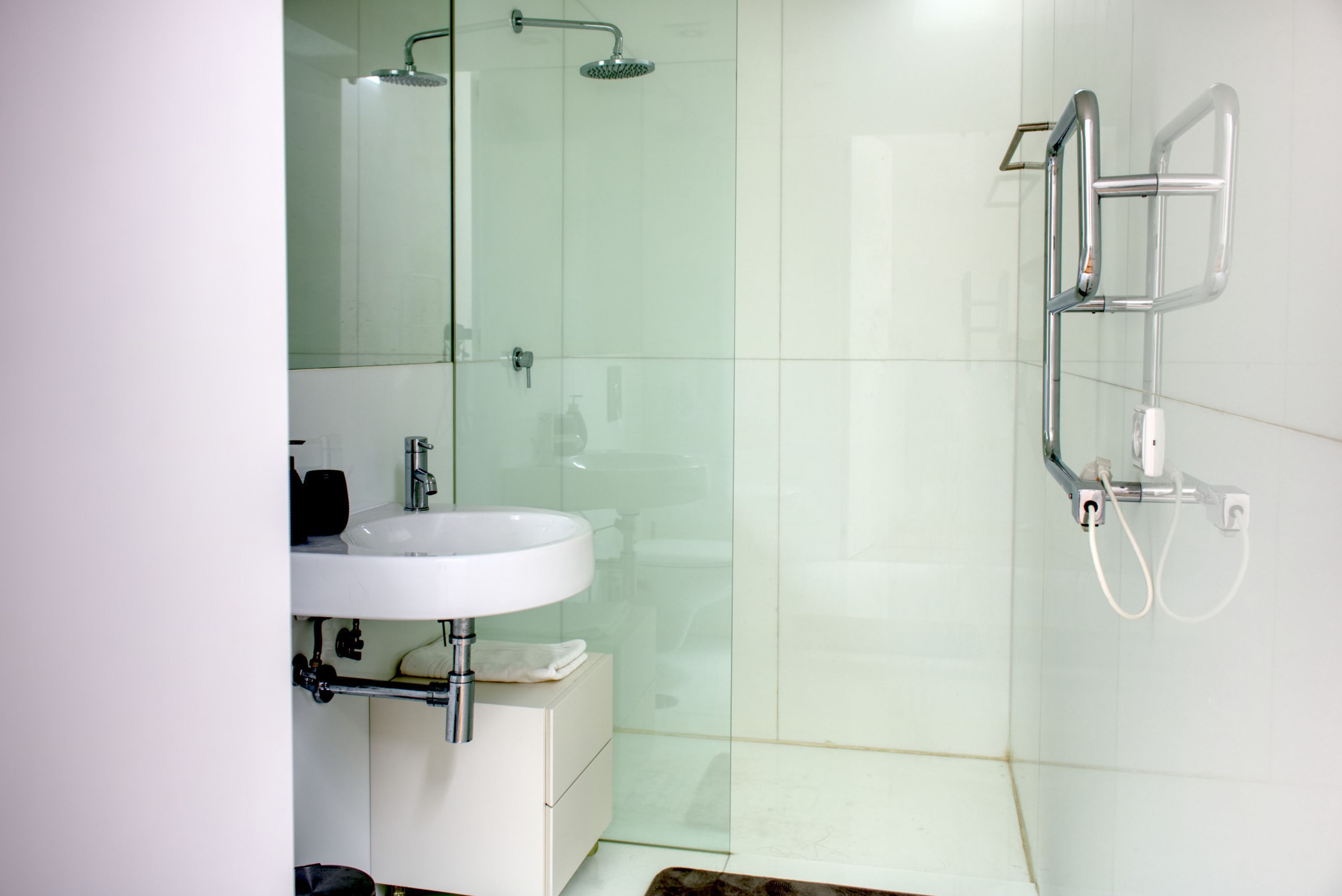 A modern bathroom with a glass shower enclosure, a white sink, and a mirror.