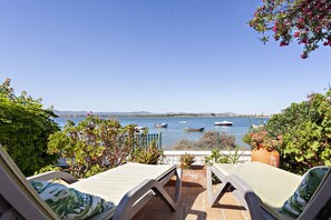 A terrace with lounge chairs overlooking a body of water with boats. - Villa Lydia in Faro With 3 Bedrooms and 1 Bathrooms (Faro)