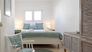 Ένα υπνοδωμάτιο με ένα κρεβάτι, δύο κομοδίνα, μια καρέκλα, ένα παράθυρο και ένα καλοριφέρ.