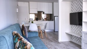 Una sala de estar moderna con un sofá, una mesa de comedor y una cocina al fondo.