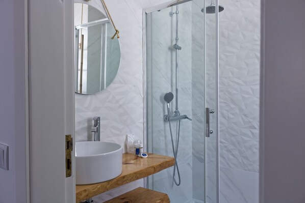 A bathroom with a white sink, wooden countertop, and a glass shower enclosure.